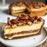 A slice of pecan pie cheesecake on a plate.