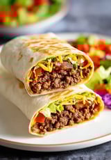 A burrito with lettuce and tomatoes.