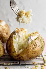 A potato with cheese dripping out of it.