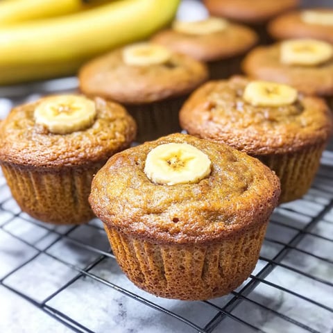 A bunch of banana muffins on a cooling rack.