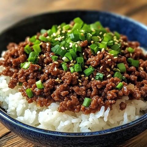 A bowl of rice with beef and green onions.